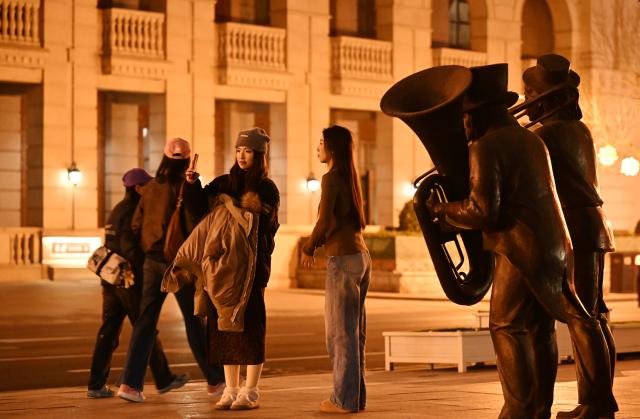 (260102) -- TIANJIN, Jan. 2, 2026 (Xinhua) -- Tourists take selfies at the Jiefang North Road historical and cultural block in Tianjin, north China, Jan. 1, 2026. Located on the south bank of the Haihe River in Tianjin, the century-old Jiefang North Road historical and cultural block used to be a neighborhood where many banks clustered. Now, the streets there decorated with festive lights have attracted many tourists for a citywalk during the New Year's Day holiday. (Xinhua/Li Ran)