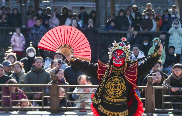 (260102) -- BEIJING, Jan. 2, 2026 (Xinhua) -- People enjoy a performance of "bianlian," a face-changing performance featured in Sichuan Opera, at Baohua Mountain National Park in Jurong, east China's Jiangsu Province on Jan. 2, 2025. China's economy kicked off 2026 with robust momentum, as evidenced by bustling economic activity in the year's first days. (Photo by Zhong Xueman/Xinhua)