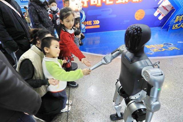 (260102) -- BEIJING, Jan. 2, 2026 (Xinhua) -- Children interact with a robot during a themed exhibition at Jiaxing Science and Technology Museum in Jiaxing, east China's Zhejiang Province, Jan. 2, 2026. Diverse exhibitions staged at museums, galleries and other cultural institutions across the country have greatly enriched people's life during the New Year holiday. (Photo by Jin Peng/Xinhua)