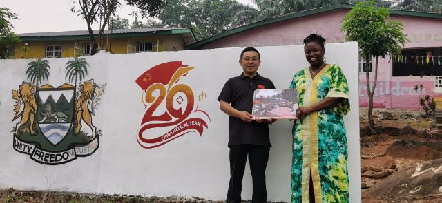 (260103) -- FREETOWN, Jan. 3, 2026 (Xinhua) -- Justina Zainab Conteh (R), executive director of the Saint George Foundation, presents a gratitude plaque to the 26th batch of the Chinese medical team to Sierra Leone at the Saint George Foundation Children's Welfare Institute in Freetown, Sierra Leone, on Jan. 2, 2026. The 26th Chinese medical team to Sierra Leone on Thursday donated a batch of supplies as New Year gifts to a welfare home in Freetown, the country's capital.
   The supplies, including rice, bread, snacks, and daily necessities, were handed over to the Saint George Foundation Children's Welfare Institute as part of the team's efforts to improve the health and daily lives of the vulnerable children in the country. (The 26th Chinese medical team to Sierra Leone/Handout via Xinhua)