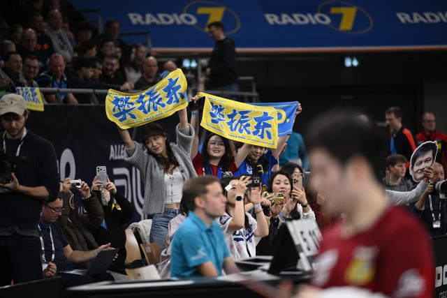 (260104) -- NEU-ULM, Jan. 4, 2026 (Xinhua) -- Fans cheer for Fan Zhendong of 1. FC Saarbrucken Tischtennis during the semifinal between 1. FC Saarbrucken Tischtennis and TTF Liebherr Ochsenhausen of Liebherr Pokal table tennis tournament in Neu-Ulm, Germany, Jan. 4, 2026. (Photo by Ulrich Hufnagel/Xinhua)