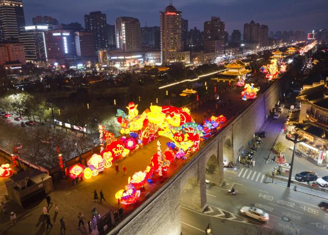 (260105) -- XI'AN, Jan. 5, 2026 (Xinhua) -- An aerial drone photo taken on Jan. 4, 2026 shows tourists watching lanterns on the ancient city wall of Xi'an during a lantern festival in Xi'an, northwest China's Shaanxi Province. A lantern festival is held here to mark the upcoming Chinese Lunar New Year. (Xinhua/Shao Rui)