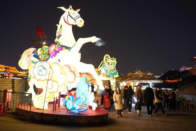 (260105) -- XI'AN, Jan. 5, 2026 (Xinhua) -- Tourists watch lanterns on the ancient city wall of Xi'an during a lantern festival in Xi'an, northwest China's Shaanxi Province, Jan. 4, 2026. A lantern festival is held here to mark the upcoming Chinese Lunar New Year. (Xinhua/Shao Rui)