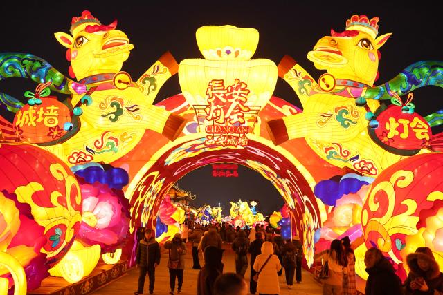 (260105) -- XI'AN, Jan. 5, 2026 (Xinhua) -- Tourists watch lanterns on the ancient city wall of Xi'an during a lantern festival in Xi'an, northwest China's Shaanxi Province, Jan. 4, 2026. A lantern festival is held here to mark the upcoming Chinese Lunar New Year. (Xinhua/Shao Rui)
