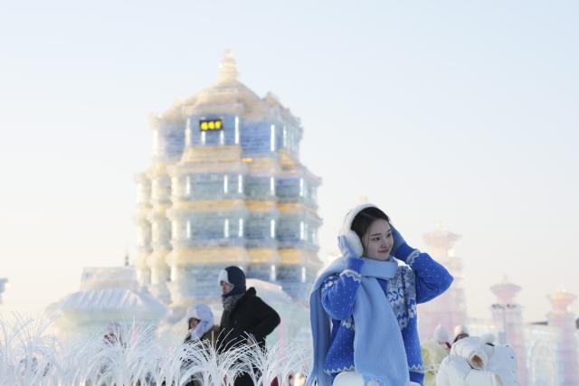 (260105) -- HARBIN, Jan. 5, 2026 (Xinhua) -- A visitor poses for photos at the Harbin Ice-Snow World in Harbin, northeast China's Heilongjiang Province, Jan. 5, 2026. The 42nd Harbin International Ice and Snow Festival kicked off at the Harbin Ice-Snow World here on Monday. (Xinhua/Wang Song)