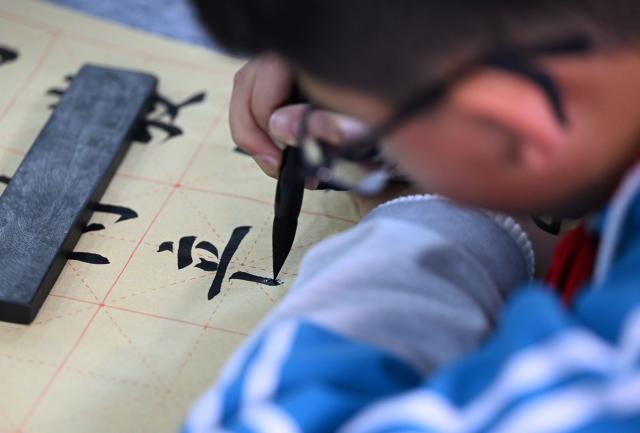 (260106) -- TIANJIN, Jan. 6, 2026 (Xinhua) -- A student writes calligraphy at the Yangcun No. 14 Primary School in Wuqing District of Tianjin, north China, Jan. 6, 2026. In recent years, this school has offered a series of classes and activities featuring traditional culture for students to experience. (Xinhua/Zhao Zishuo)