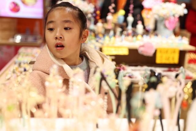 (260107) -- LANZHOU, Jan. 7, 2026 (Xinhua) -- A girl selects accessories at a store in Qilihe District of Lanzhou, northwest China's Gansu Province, on Jan. 6, 2026. At the beginning of the new year, Lanzhou has been actively creating a festive atmosphere and promoting the upgrading of mature business districts and characteristic streets in the urban area. A series of new products and services has been launched to boost the consumption. (Xinhua/Chen Bin)