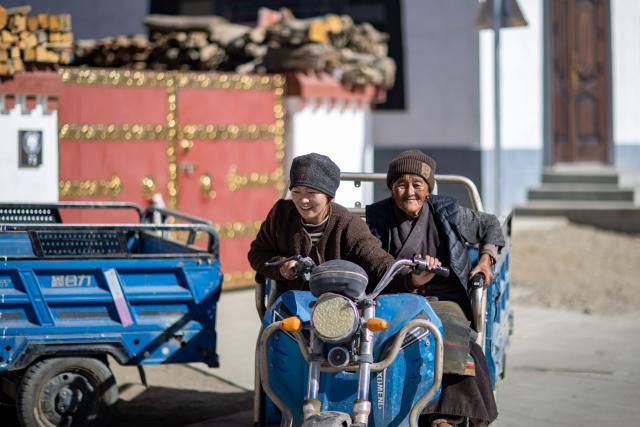 (260107) -- XIGAZE, Jan. 7, 2026 (Xinhua) -- Villagers ride a tricycle in Zimgag Village of Chamco Township, in Dingri County of Xigaze City, southwest China's Xizang Autonomous Region, on Jan. 5, 2026. In January 2025, a 6.8-magnitude earthquake struck Dingri County in the city of Xigaze, leveling thousands of houses.
  Ten months after the earthquake, more than 32,500 destroyed or damaged houses have been restored and handed over to affected residents. 
   In Zimgag Village, one of the villages hardest hit by the earthquake, new houses are neat and sturdy and supporting facilities are well-equipped. People live a stable and pleasant life here. (Xinhua/Jiang Fan)