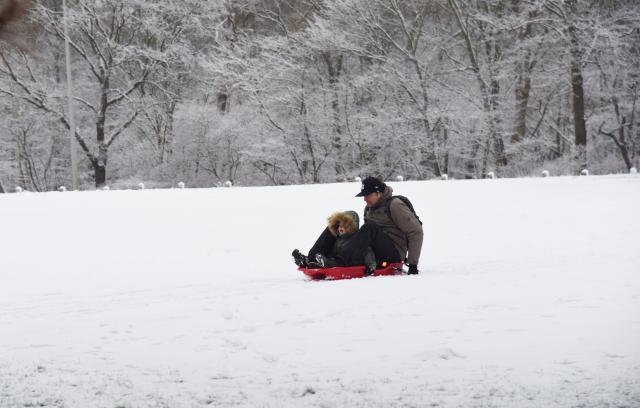 (260107) -- THE HAGUE, Jan. 7, 2026 (Xinhua) -- A man and a child enjoy sledding in the snow in the Hague, the Netherlands, Jan. 7, 2026. The Royal Netherlands Meteorological Institute (KNMI) issued a code orange snowfall warning on Wednesday, with some areas of the Netherlands receiving up to 10 centimeters of snow. (Xinhua/Shao Haijun)