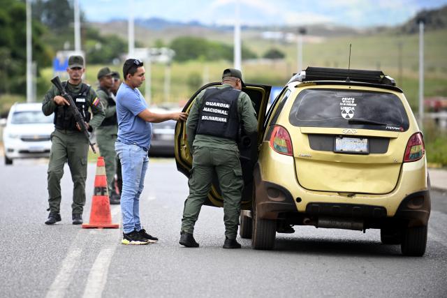 (260107) -- PACARAIMA, Jan. 7, 2026 (Xinhua) -- In this photo taken in Pacaraima, Roraima, Brazil, a member of the Bolivarian National Guard of Venezuela inspects a vehicle near the border between Brazil and Venezuela on Jan. 6, 2026. (Photo by Lucio Tavora/Xinhua)