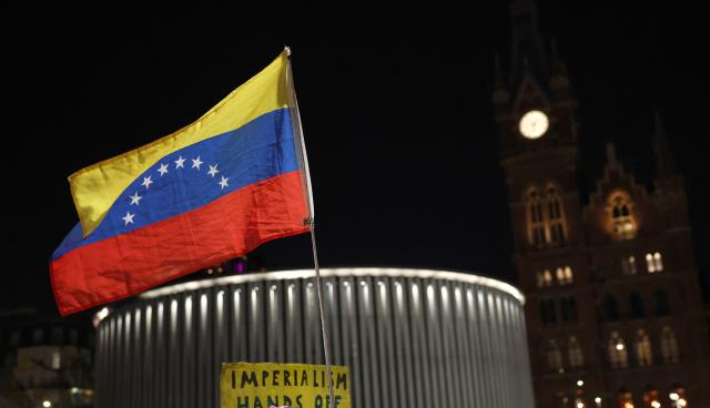 (260108) -- LONDON, Jan. 8, 2026 (Xinhua) -- A demonstrator holds a national flag of Venezuela during a protest condemning U.S. attack on Venezuela outside King's Cross railway station in London, Britain, Jan. 7, 2026. (Xinhua/Li Ying)