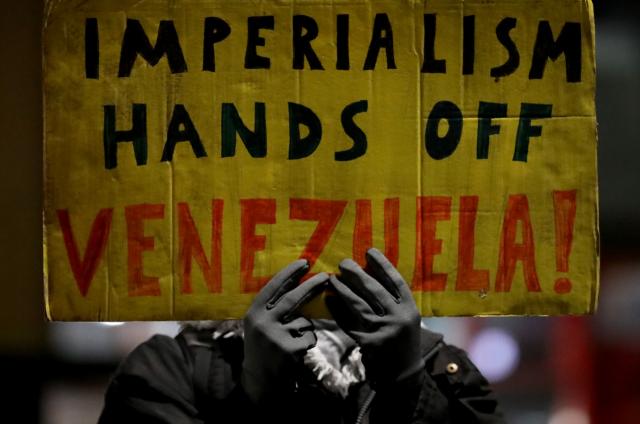 (260108) -- LONDON, Jan. 8, 2026 (Xinhua) -- A demonstrator holds a placard during a protest condemning U.S. attack on Venezuela outside King's Cross railway station in London, Britain, Jan. 7, 2026. (Xinhua/Li Ying)