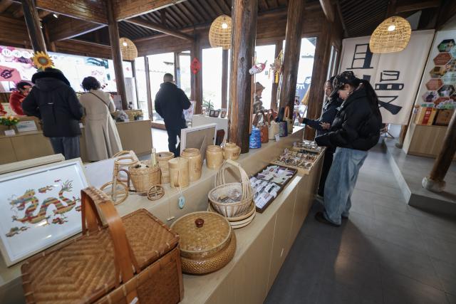 (260108) -- JINHUA, Jan. 8, 2026 (Xinhua) -- People shop at a traditional handicraft store in Poyang ancient street in Jindong District of Jinhua City, east China's Zhejiang Province, on Jan. 8, 2026. In recent years, Jindong District of Jinhua City has developed the cultural and tourism industry by leveraging its cultural, sports and music resources, creating new consumption scenarios for tourism with distinctive features, including sports parks, camping bases, old rural streets and ceramic art galleries. (Xinhua/Xu Yu)