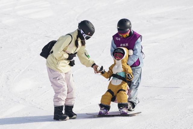 (260108) -- SHUOZHOU, Jan. 8, 2026 (Xinhua) -- A child practices snowboarding with the help of a coach (R) at the Guangwu international ski resort in Shanyin County of Shuozhou, north China's Shanxi Province, Jan. 7, 2026. Shanyin County has been leveraging its geographical advantage to develop ice and snow-themed tourism, which is now a new driver for the local economy. (Xinhua/Yang Chenguang)