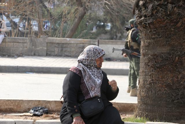 (260108) -- DAMASCUS, Jan. 8, 2026 (Xinhua) -- An elderly woman sits by the roadside outside the Ashrafieh neighborhood in Aleppo city, Syria, Jan. 8, 2026. The Syrian army on Thursday launched intense shelling targeting positions of the Syrian Democratic Forces (SDF) in the Sheikh Maqsoud and Ashrafieh neighborhoods of Aleppo, the state-run SANA news agency reported. (Str/Xinhua)