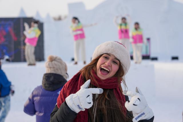 (260109) -- HARBIN, Jan. 9, 2026 (Xinhua) -- A foreign tourist dances to the music while visiting the 38th Sun Island International Snow Sculpture Art Expo in Harbin, northeast China's Heilongjiang Province, Jan. 8, 2026.
  The ongoing snow sculpture art expo, with an exhibition area of 1.5 million square meters, is attracting visitors to its stunning ice and snow landscapes. (Xinhua/Wang Jianwei)