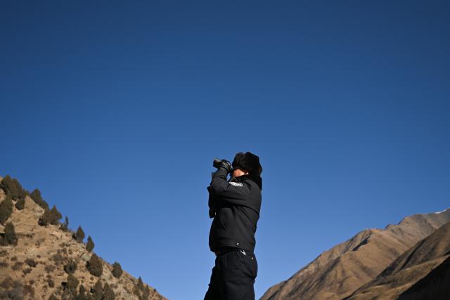 (260109) -- MENYUAN, Jan. 9, 2026 (Xinhua) -- Police officer Guo Jianye observes with a telescope in the Laohugou region of Menyuan Hui Autonomous County in Haibei Tibetan Autonomous Prefecture, northwest China's Qinghai Province, Jan. 9, 2026. For years, police officers and rangers inside Qilian Mountain National Park in northwest China's Qinghai Province have dedicated themselves to their work, carrying out regular patrols and safeguarding the region's ecological security despite high altitude and harsh winter weather. (Xinhua/Zhang Long)