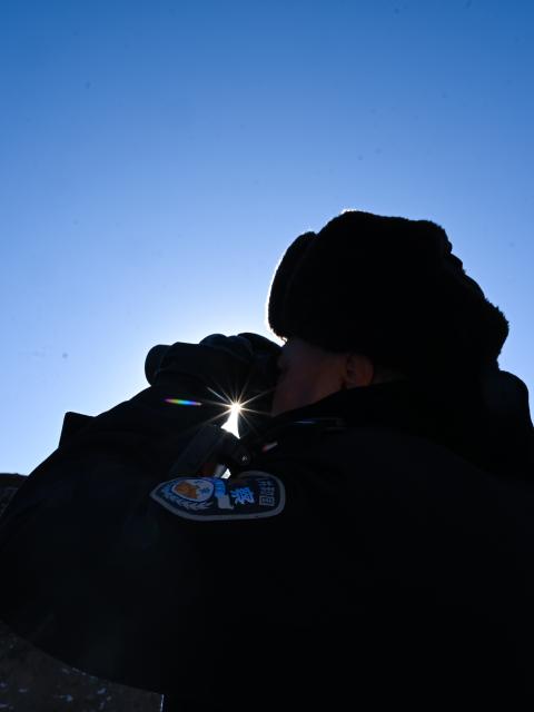 (260109) -- MENYUAN, Jan. 9, 2026 (Xinhua) -- Police officer Guo Jianye observes with a telescope in the Laohugou region of Menyuan Hui Autonomous County in Haibei Tibetan Autonomous Prefecture, northwest China's Qinghai Province, Jan. 9, 2026. For years, police officers and rangers inside Qilian Mountain National Park in northwest China's Qinghai Province have dedicated themselves to their work, carrying out regular patrols and safeguarding the region's ecological security despite high altitude and harsh winter weather. (Xinhua/Zhang Long)