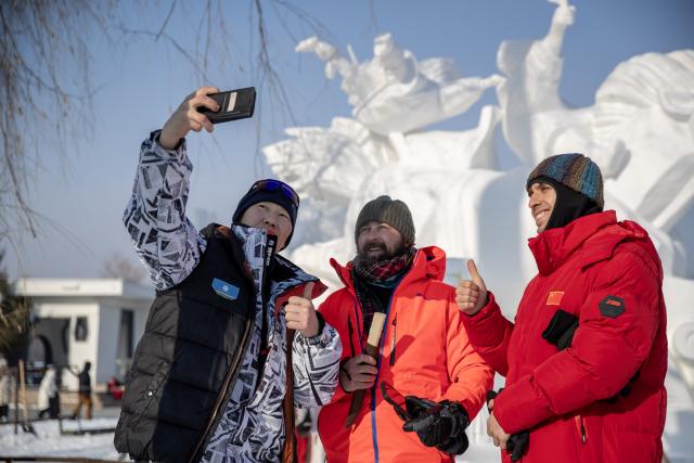 (260110) -- HARBIN, Jan. 10, 2026 (Xinhua) -- Artists pose for a group photo in front of a snow sculpture at the venue of Sun Island Snow Expo in Harbin, northeast China's Heilongjiang Province, Jan. 9, 2026. A four-day snow sculpture competition concluded here on Friday, with the participation of 25 teams from 13 countries. (Photo by Zhang Dawei/Xinhua)