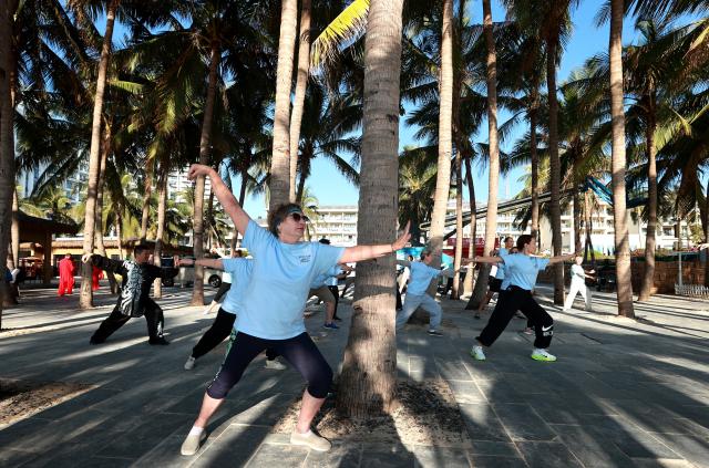 (260110) -- SANYA, Jan. 10, 2026 (Xinhua) -- Foreign tourists learn Tai Chi under coconut groves at the Dadonghai scenic area in Sanya, south China's Hainan Province, Jan. 9, 2026. (Photo by Yuan Yongdong/Xinhua)