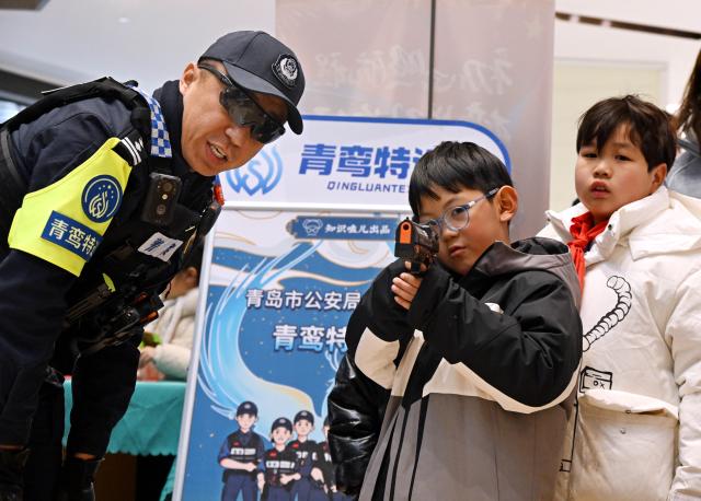 (260110) -- BEIJING, Jan. 10, 2026 (Xinhua) -- A boy tries simulated shooting in Qingdao, east China's Shandong Province, Jan. 10, 2026. Various activities were held nationwide to mark the sixth Chinese People's Police Day. (Xinhua/Li Ziheng)