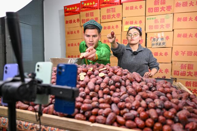 (260110) -- MOYU, Jan. 10, 2026 (Xinhua) -- Staff members promote products via live-streaming at a network technology company in Moyu County, Hotan Prefecture, northwest China's Xinjiang Uygur Autonomous Region, Jan. 9, 2026. Premium Xinjiang goods like walnuts and red jujubes, which are popular choices for customers nationwide for the Chinese New Year, have entered their peak sales season as the Spring Festival approaches. E-commerce companies in Hotan are leveraging live-streaming sales and online shopping festivals to promote high-quality agricultural products of Xinjiang, boosting farmers' incomes and rural revitalization. (Xinhua/Ding Lei)