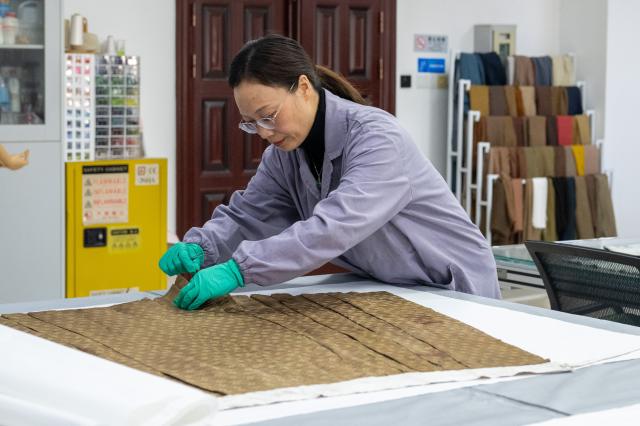 (260110) -- WUHAN, Jan. 10, 2026 (Xinhua) -- Chen Shaohui, head of the textile cultural relics restoration department, checks a textile cultural relic at the cultural relics protection center in Jingzhou, central China's Hubei Province, Jan. 9, 2026. Organic cultural relics represented by bamboo slips pose significant challenges in cultural relic preservation. In recent years, the cultural relics protection center in Jingzhou of Hubei Province has focused on innovation and application of preservation techniques for organic cultural relics, striving to ensure comprehensive care for such items. (Xinhua/Du Zixuan)