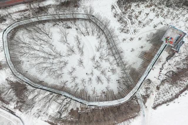 (260110) -- SHENYANG, Jan. 10, 2026 (Xinhua) -- An aerial drone photo shows visitors experiencing ice slide at a hot spring resort in Shenyang, northeast China's Liaoning Province, Jan. 9, 2026. Leveraging its unique natural resources, Shenyang offers special winter tourism experiences by combining ice-and-snow activities with hot springs, attracting visitors from across the country. (Xinhua/Pan Yulong)