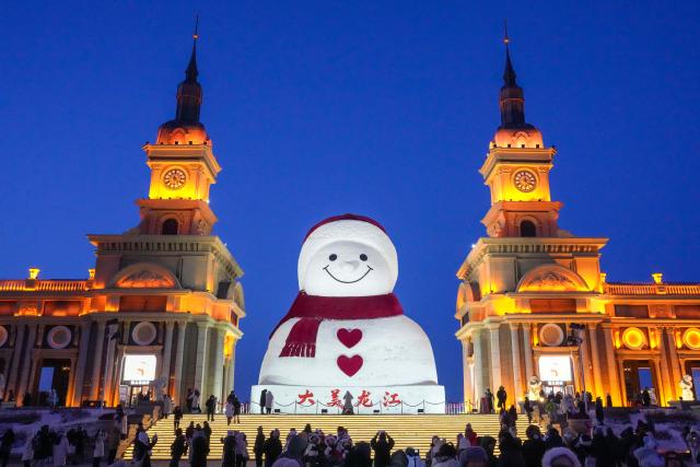 (260111) -- HARBIN, Jan. 11, 2026 (Xinhua) -- Tourists take photos of the iconic giant snowman at the Qunli music park in Harbin, northeast China's Heilongjiang Province, Jan. 10, 2026.
  Standing 19 meters tall, measuring 14 meters in length and 11 meters in width, the snowman was dug and carved out of over 3,500 cubic meters of snow, with tourists swarming to take pictures of its classic red scarf and round face. (Xinhua/Wang Jianwei)