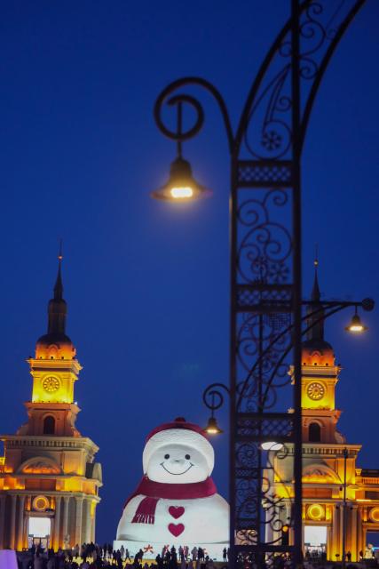 (260111) -- HARBIN, Jan. 11, 2026 (Xinhua) -- Tourists take photos of the iconic giant snowman at the Qunli music park in Harbin, northeast China's Heilongjiang Province, Jan. 10, 2026.
  Standing 19 meters tall, measuring 14 meters in length and 11 meters in width, the snowman was dug and carved out of over 3,500 cubic meters of snow, with tourists swarming to take pictures of its classic red scarf and round face. (Xinhua/Wang Jianwei)