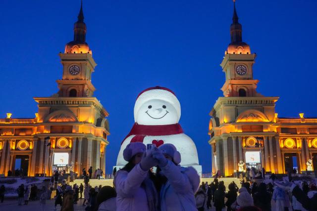 (260111) -- HARBIN, Jan. 11, 2026 (Xinhua) -- Tourists take selfie in front of the iconic giant snowman at the Qunli music park in Harbin, northeast China's Heilongjiang Province, Jan. 10, 2026.
  Standing 19 meters tall, measuring 14 meters in length and 11 meters in width, the snowman was dug and carved out of over 3,500 cubic meters of snow, with tourists swarming to take pictures of its classic red scarf and round face. (Xinhua/Wang Jianwei)