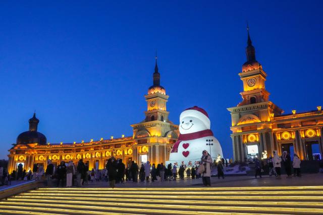 (260111) -- HARBIN, Jan. 11, 2026 (Xinhua) -- Tourists take photos of the iconic giant snowman at the Qunli music park in Harbin, northeast China's Heilongjiang Province, Jan. 10, 2026.
  Standing 19 meters tall, measuring 14 meters in length and 11 meters in width, the snowman was dug and carved out of over 3,500 cubic meters of snow, with tourists swarming to take pictures of its classic red scarf and round face. (Xinhua/Wang Jianwei)