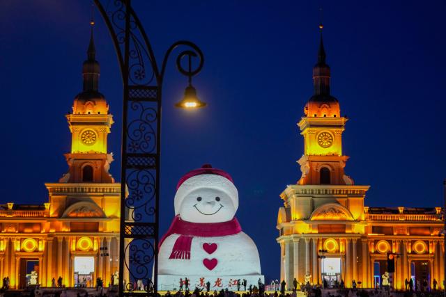 (260111) -- HARBIN, Jan. 11, 2026 (Xinhua) -- Tourists take photos of the iconic giant snowman at the Qunli music park in Harbin, northeast China's Heilongjiang Province, Jan. 10, 2026.
  Standing 19 meters tall, measuring 14 meters in length and 11 meters in width, the snowman was dug and carved out of over 3,500 cubic meters of snow, with tourists swarming to take pictures of its classic red scarf and round face. (Xinhua/Wang Jianwei)