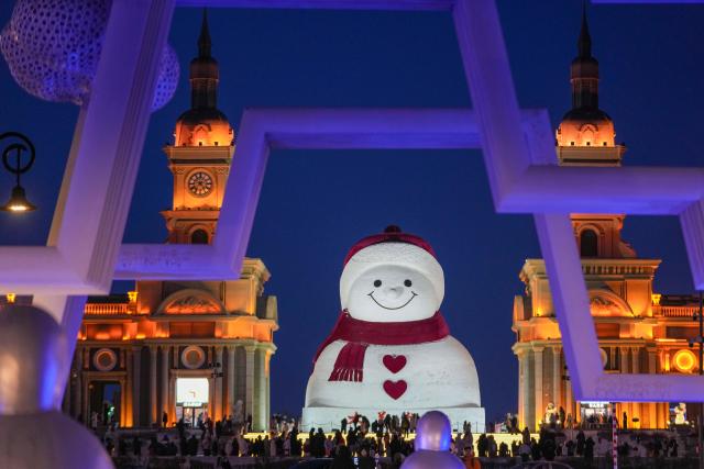 (260111) -- HARBIN, Jan. 11, 2026 (Xinhua) -- Tourists take photos of the iconic giant snowman at the Qunli music park in Harbin, northeast China's Heilongjiang Province, Jan. 10, 2026.
  Standing 19 meters tall, measuring 14 meters in length and 11 meters in width, the snowman was dug and carved out of over 3,500 cubic meters of snow, with tourists swarming to take pictures of its classic red scarf and round face. (Xinhua/Wang Jianwei)