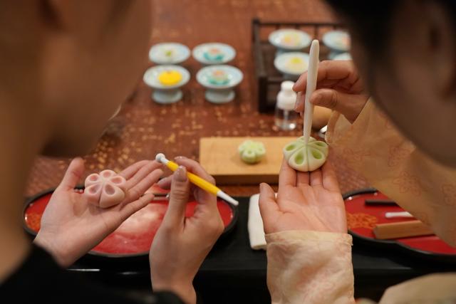 (260111) -- XI'AN, Jan. 11, 2026 (Xinhua) -- A tourist (L) learns to make a Tangguozi dessert from a staff member during a hands-on Tangguozi workshop in Xi'an, northwest China's Shaanxi Province, Jan. 9, 2026. Tangguozi, a sort of desserts inspired by the culture from the Tang Dynasty (618-907), features exquisite designs and vibrant colors, often served with tea. They are now going through a modern revival.
   Bearing years of experience in baking, Li Huan accidentally learned about Tangguozi and co-founded a company specialized in this business in 2020. Li believes that traditional culture is an inexhaustible source of creativity. She and her team often visit museums, drawing inspiration from the patterns and designs of artifacts from the Tang Dynasty. They carefully adjust the recipes by combining healthy diets with modern taste, which made their Tangguozi products increasingly popular.
    Li and her team have expanded their business approach by introducing Tangguozi and tea culture of the Tang Dynasty to domestic and international cultural exchange events, and hosting hands-on workshops for tourists and study groups. They also offer comprehensive services such as event planning and crafts training to make Tangguozi and the Tang culture more tangible and accessible to ordinary people. (Xinhua/Shao Rui)