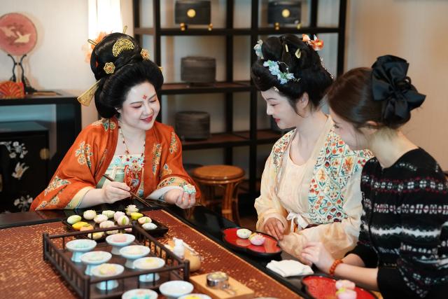 (260111) -- XI'AN, Jan. 11, 2026 (Xinhua) -- Li Huan (L), a staff member (C) and a tourist communicate during a hands-on Tangguozi workshop in Xi'an, northwest China's Shaanxi Province, Jan. 9, 2026. Tangguozi, a sort of desserts inspired by the culture from the Tang Dynasty (618-907), features exquisite designs and vibrant colors, often served with tea. They are now going through a modern revival.
   Bearing years of experience in baking, Li Huan accidentally learned about Tangguozi and co-founded a company specialized in this business in 2020. Li believes that traditional culture is an inexhaustible source of creativity. She and her team often visit museums, drawing inspiration from the patterns and designs of artifacts from the Tang Dynasty. They carefully adjust the recipes by combining healthy diets with modern taste, which made their Tangguozi products increasingly popular.
    Li and her team have expanded their business approach by introducing Tangguozi and tea culture of the Tang Dynasty to domestic and international cultural exchange events, and hosting hands-on workshops for tourists and study groups. They also offer comprehensive services such as event planning and crafts training to make Tangguozi and the Tang culture more tangible and accessible to ordinary people. (Xinhua/Shao Rui)