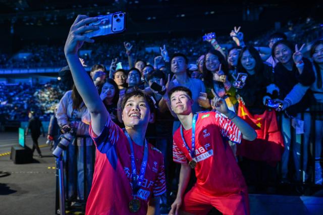 (260111) -- KUALA LUMPUR, Jan. 11, 2026 (Xinhua) -- Feng Yanzhe (front R)/Huang Dongping of China take a selfie with audience after the mixed doubles final match against Jiang Zhenbang/Wei Yaxin of China at the Malaysia Open 2026 badminton tournament in Kuala Lumpur, Malaysia, Jan. 11, 2026. (Photo by Chong Voon Chung/Xinhua)