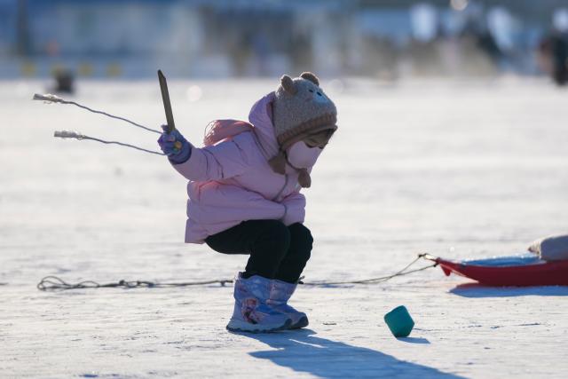 (260111) -- HARBIN, Jan. 11, 2026 (Xinhua) -- A child plays on the frozen surface of the Songhua River in Harbin, northeast China's Heilongjiang Province, Jan. 10, 2026. The surface of the Harbin section of Songhua River, now solidly frozen, serves as a "fun field," where locals and tourists alike enjoy themselves with ice-and-snow-themed amusements. (Xinhua/Wang Jianwei)