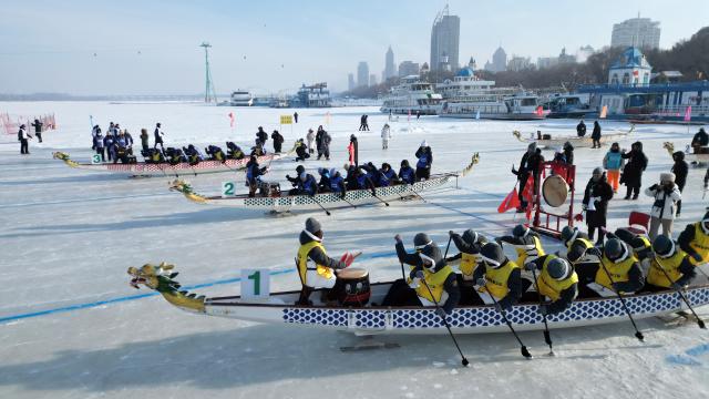 (260111) -- HARBIN, Jan. 11, 2026 (Xinhua) -- A drone photo taken on Jan. 9, 2026 shows people participating in a "dragon boat" competition on the frozen surface of the Songhua River in Harbin, northeast China's Heilongjiang Province. The surface of the Harbin section of Songhua River, now solidly frozen, serves as a "fun field," where locals and tourists alike enjoy themselves with ice-and-snow-themed amusements. (Photo by Liu Yang/Xinhua)