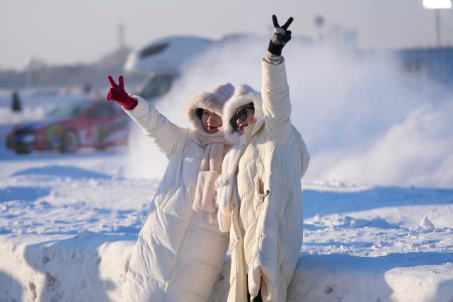 (260111) -- HARBIN, Jan. 11, 2026 (Xinhua) -- Tourists pose for photos on the frozen surface of the Songhua River in Harbin, northeast China's Heilongjiang Province, Jan. 10, 2026. The surface of the Harbin section of Songhua River, now solidly frozen, serves as a "fun field," where locals and tourists alike enjoy themselves with ice-and-snow-themed amusements. (Xinhua/Wang Jianwei)