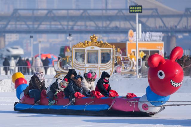 (260111) -- HARBIN, Jan. 11, 2026 (Xinhua) -- Tourists play on the frozen surface of the Songhua River in Harbin, northeast China's Heilongjiang Province, Jan. 11, 2026. The surface of the Harbin section of Songhua River, now solidly frozen, serves as a "fun field," where locals and tourists alike enjoy themselves with ice-and-snow-themed amusements. (Xinhua/Wang Jianwei)