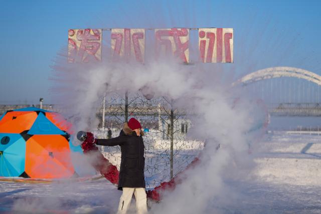 (260111) -- HARBIN, Jan. 11, 2026 (Xinhua) -- A tourist plays a "water to ice" stunt by splashing water into the cold air on the frozen surface of the Songhua River in Harbin, northeast China's Heilongjiang Province, Jan. 10, 2026. The surface of the Harbin section of Songhua River, now solidly frozen, serves as a "fun field," where locals and tourists alike enjoy themselves with ice-and-snow-themed amusements. (Xinhua/Wang Jianwei)