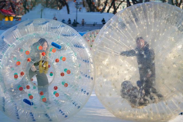(260111) -- HARBIN, Jan. 11, 2026 (Xinhua) -- Tourists play on the frozen surface of the Songhua River in Harbin, northeast China's Heilongjiang Province, Jan. 10, 2026. The surface of the Harbin section of Songhua River, now solidly frozen, serves as a "fun field," where locals and tourists alike enjoy themselves with ice-and-snow-themed amusements. (Xinhua/Wang Jianwei)