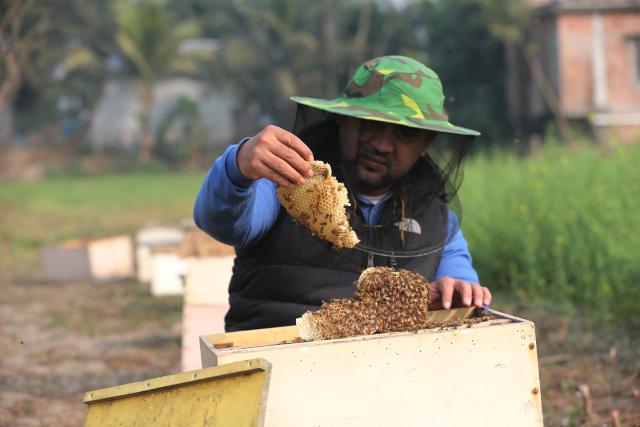 (260111) -- MUNSHIGANJ, Jan. 11, 2026 (Xinhua) -- A beekeeper extracts a fraction of a honeycomb in a field in Munshiganj, Bangladesh, Jan. 11, 2026. (Photo by Habibur Rahman/Xinhua)