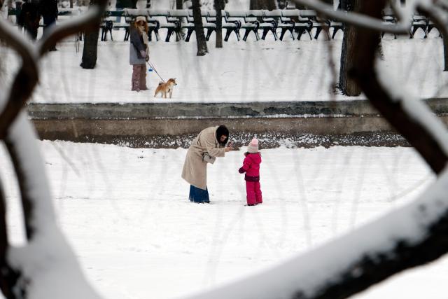 (260112) -- BUCHAREST, Jan. 12, 2026 (Xinhua) -- A woman takes pictures of a child amid snowfall at a park in Bucharest, Romania, on Jan. 11, 2026.
  Romania is facing a severe winter episode, with snowfall, blizzards, persistent frost and extremely low temperatures in large parts of the country. (Photo by Cristian Cristel/Xinhua)