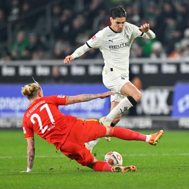 (260112) -- MOENCHENGLADBACH, Jan. 12, 2026 (Xinhua) -- Kevin Diks (top) of Borussia Moenchengladbach vies with Marius Wolf of FC Augsburg during the German first division of Bundesliga football match between Borussia Moenchengladbach and FC Augsburg in Moenchengladbach, Germany, Jan. 11, 2026. (Photo by Ulrich Hufnagel/Xinhua)