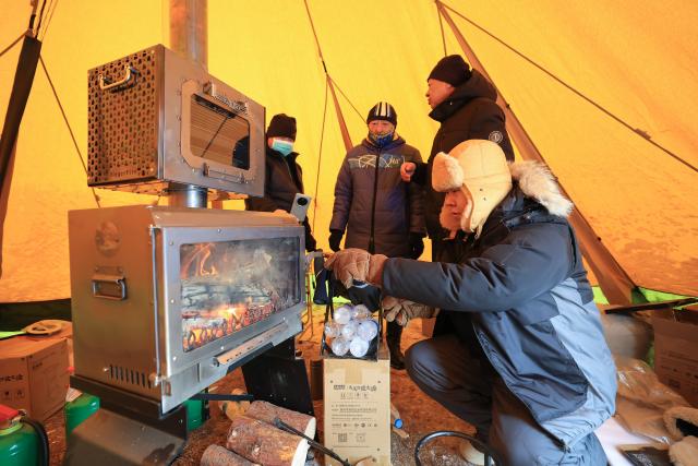 (260112) -- QIQIHAR, Jan. 12, 2026 (Xinhua) -- Camping enthusiasts make a fire inside a tent during a camping festival in Qiqihar City, northeast China's Heilongjiang Province, on Jan. 12, 2026. The week-long camping festival opened here on Monday, where camping enthusiasts and tourists across China are allowed to experience the unique charm of camping and local folk customs in frigid chilliness. (Photo by Xu Shuai/Xinhua)