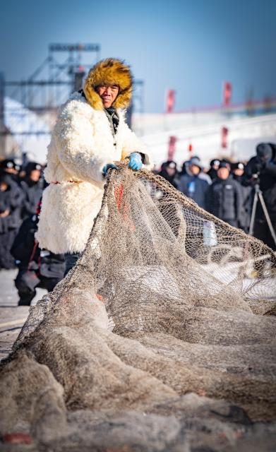 (260112) -- HOHHOT, Jan. 12, 2026 (Xinhua) -- This photo taken on Jan. 10, 2026 shows a fisherman pulling a net out of the frozen surface of the lake during the fourth Hasuhai winter fishing festival in Hohhot, north China's Inner Mongolia Autonomous Region. Hohhot has launched more than 300 winter amusement programs since December 2025, incorporating ice and snow sports, cultural experiences and vogue consumption to boost the local economy. (Photo by Xu Ting/Xinhua)