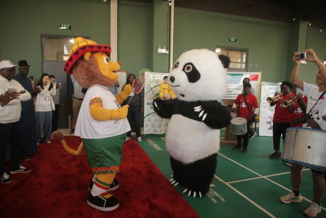 (260112) -- DAKAR, Jan. 12, 2026 (Xinhua) -- Ayo (front L), the lion mascot of the Dakar 2026 Youth Olympic Games, and a Chinese panda mascot prepared by the Chinese Embassy in Senegal interact during the second "Panda Cup" China-Senegal Badminton Friendship Tournament at the Leopold Sedar Senghor Stadium in Dakar, Senegal, Jan. 11, 2026. TO GO WITH "Feature: Panda Cup badminton event builds China-Senegal sporting ties" (Photo by Aliou Mbaye/Xinhua)
