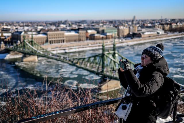(260112) -- BUDAPEST, Jan. 12, 2026 (Xinhua) -- A woman takes photos of the Danube River with drifting ice floes in Budapest, Hungary, on Jan. 12, 2026. (Photo by David Balogh/Xinhua)